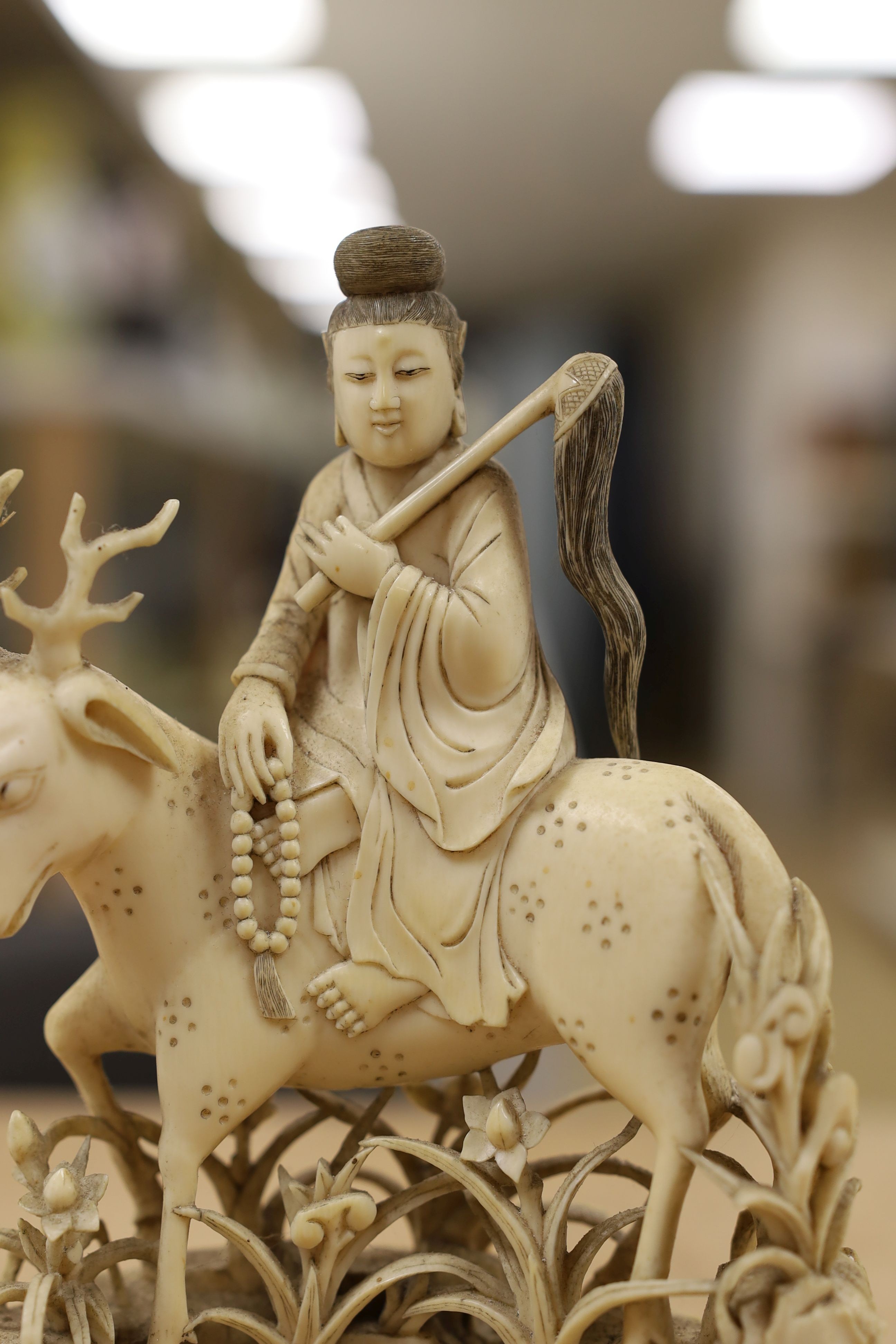 A Chinese carved ivory figure of a female immortal riding a deer, early 20th century, height 17cm excl. stand